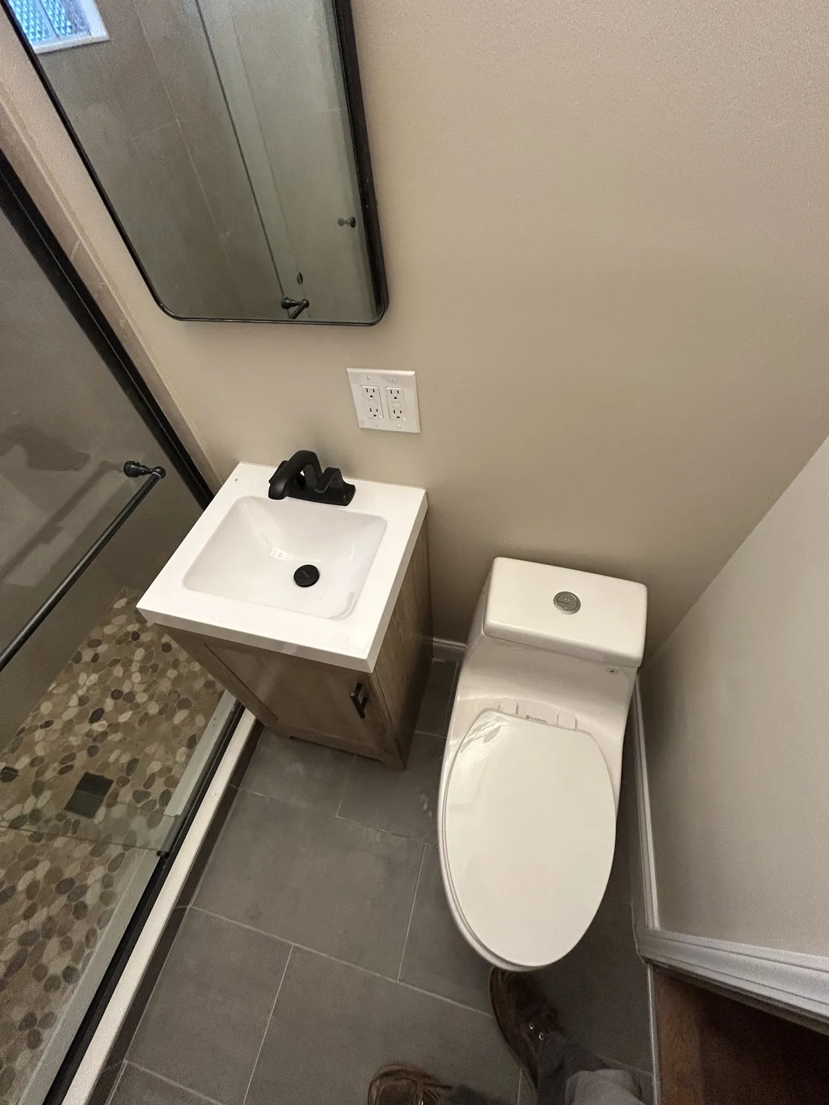 Compact bathroom with floating vanity, pebble accent band, and large-format gray tile